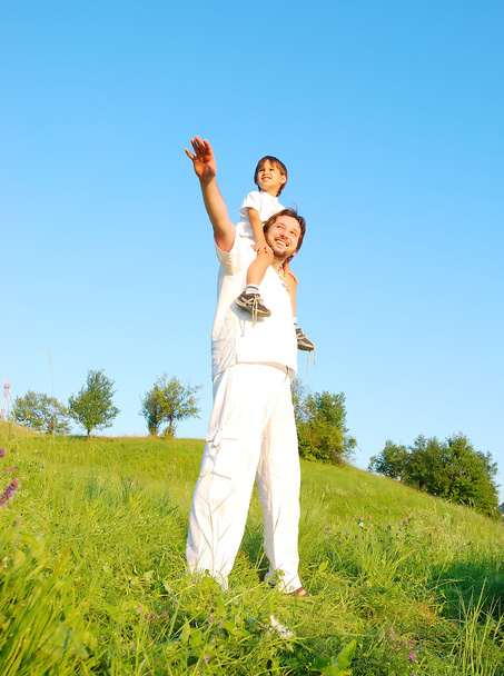 Young father in white with little boy on beautiful meadow - Foto, afbeelding