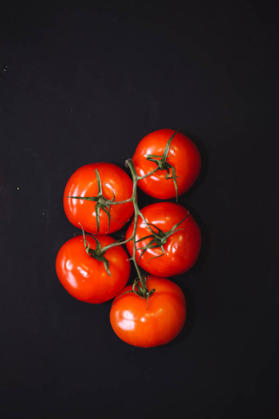 Ripe red tomatoes on black background, top view. The whole vegetable. close up - 写真・画像