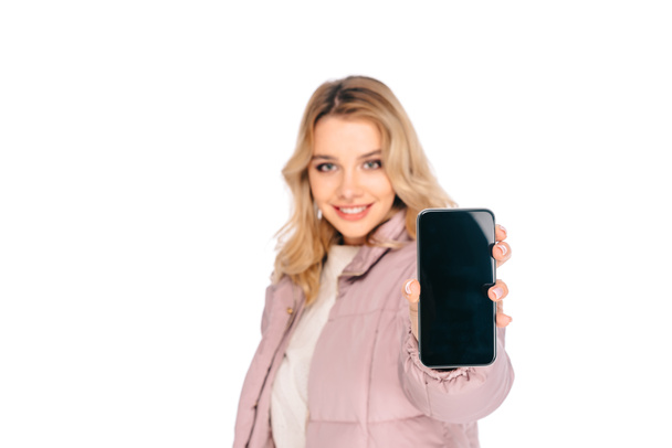 young woman holding smartphone with blank screen and smiling at camera isolated on white  - Foto, Imagem