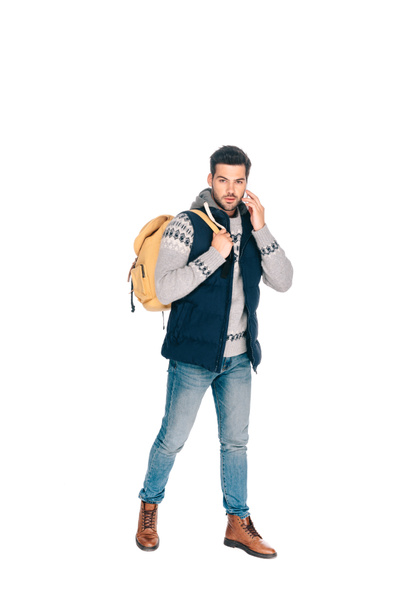 handsome young man with backpack talking by smartphone and looking at camera isolated on white - Фото, зображення