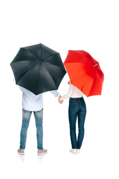 back view of young couple with black and red umbrellas holding hands isolated on white - Fotoğraf, Görsel