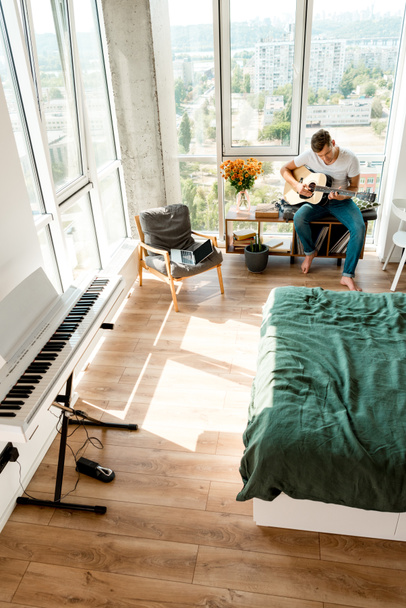 high angle view of young man playing acoustic guitar at home - Photo, Image