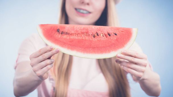 Happy cheerful teenage girl ready for summer holding sweet fruit red juicy watermelon, on blue - Foto, Imagem