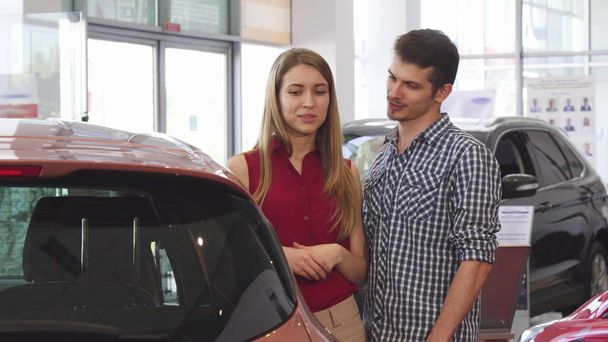 Beautiful couple examining new automobile at the dealership - Photo, Image