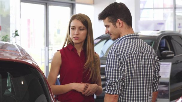 Young beautiful woman talking to her man at the dealership - Photo, Image