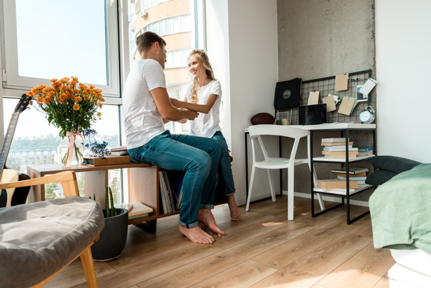 smiling young couple in love in casual clothing at home - Foto, afbeelding