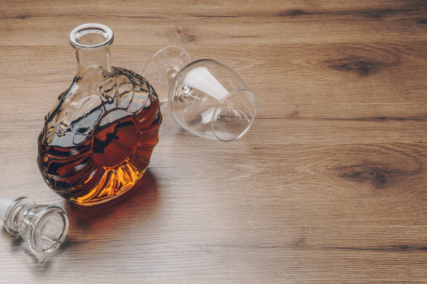 un decantador de brandy con un vaso de snifter vacío sobre la mesa de madera
 - Foto, Imagen