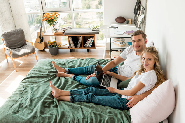 high angle view of young couple with digital laptop resting on bed at home - Photo, Image