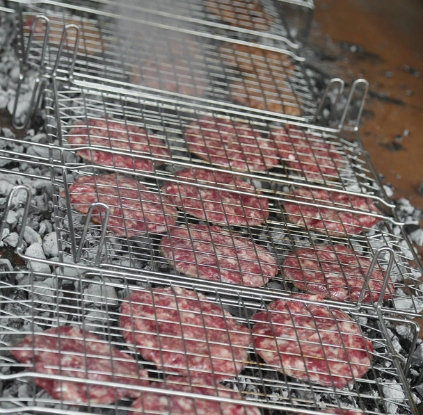 veel rundvlees hamburgers gekookt op de roosters van de open haard op een festival - Foto, afbeelding