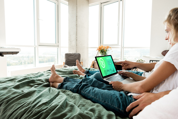 Çift yatağa evde istirahat ekran yazı alışveriş ile dijital dizüstü bilgisayar ile kısmi görünümü - Fotoğraf, Görsel
