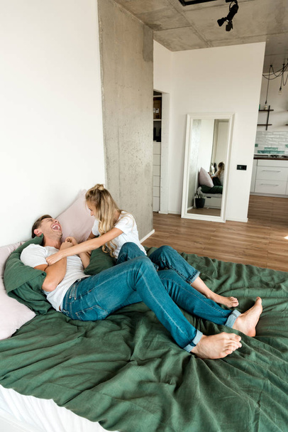 glückliches junges Paar, das zu Hause zusammen im Bett liegt - Foto, Bild