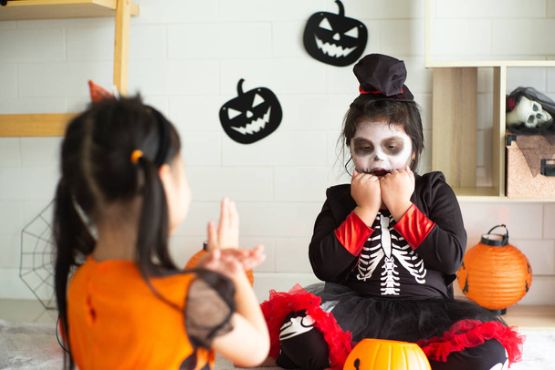 Retrato de dos hermanas disfrazadas de Halloween actuando como una expresión de frigthening fantasma entre sí en el festival de Halloween
 - Foto, Imagen
