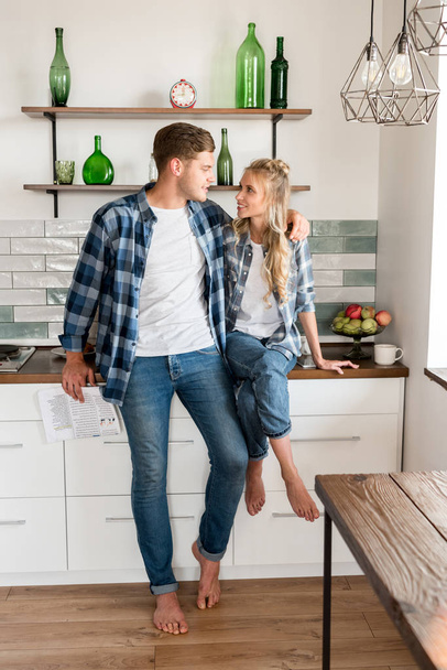 smiling loving couple in casual clothing in kitchen at home - Photo, Image