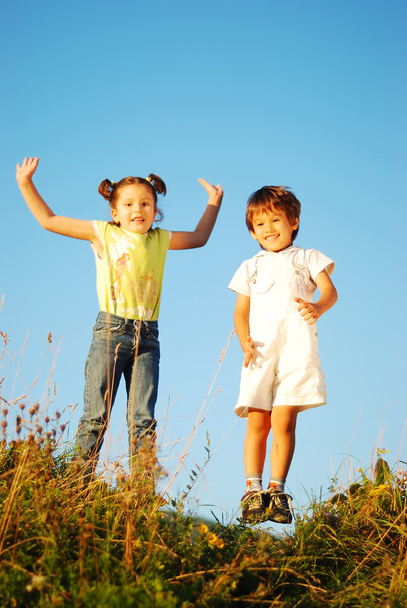幸せな少女と子供のジャンプと自然の中で楽しみを分かち合えるところ - 写真・画像