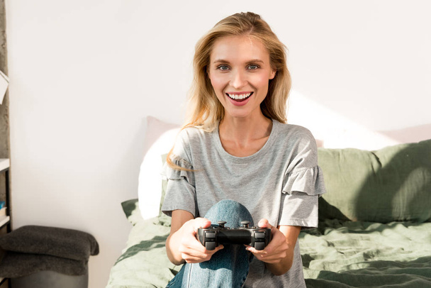 retrato de joven mujer alegre con gamepad en casa
 - Foto, imagen