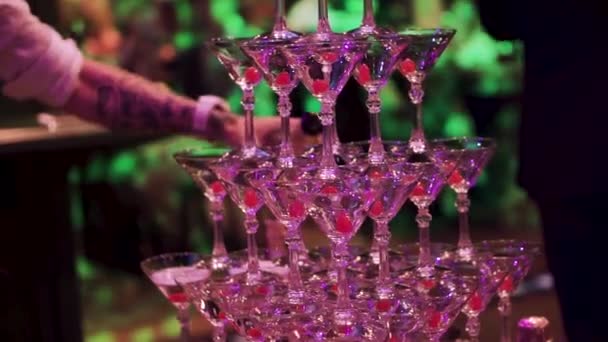 Gläser mit Martini-Cocktail mit UV-Beleuchtung. Clip. Champagner-Rutsche. Pyramide oder Brunnen aus Sektgläsern mit Kirsche und Dampf aus Trockeneis. leere Gläser Martini in - Filmmaterial, Video
