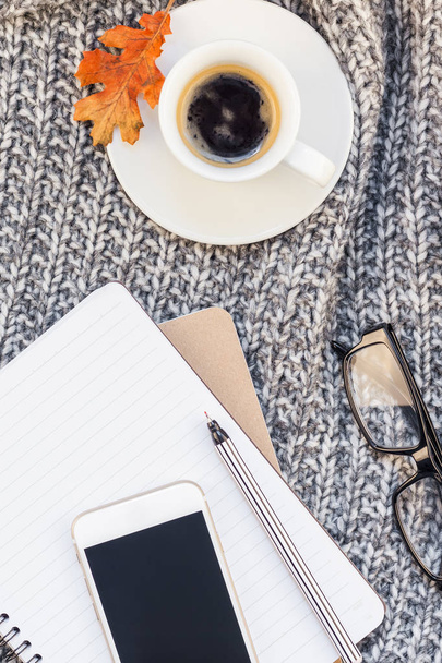 Kreatív ősz lapos smartphone notebook kávé csésze hangulatos szürke kötött kockás háttér másol hely fölött felülnézet elegáns otthonom munkaterület feküdt. Őszi szezon sablon női blog szociális média - Fotó, kép