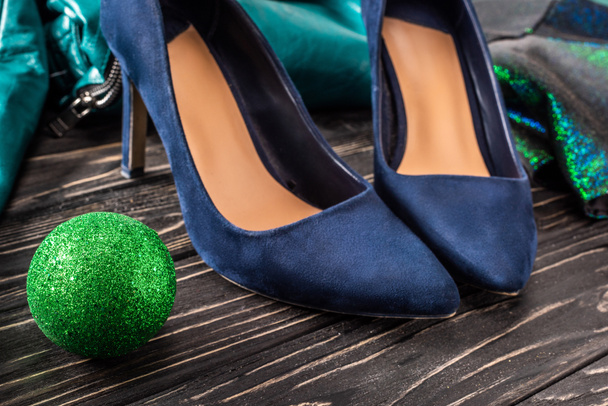vue rapprochée de chaussures bleues féminines lumineuses et boule de chirstmas verte sur la surface en bois
 - Photo, image