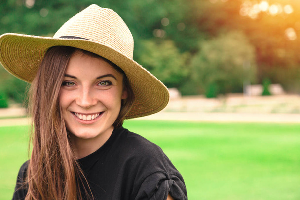 Young beautiful woman in straw hat in park in summer - 写真・画像