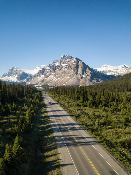 Aerial view of a scenic road in the Canadian Rockies during a vibrant sunny summer day. Taken in Icefields Parkway, Banff, Alberta, Canada. - Foto, Imagen