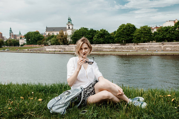Una joven en el río Vístula en Cracovia. Chica con estilo en gafas de sol habla en su teléfono. Vista de la ciudad de Cracovia. Polonia
. - Foto, imagen
