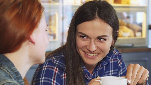 Красивая молодая женщина пьет кофе со своей подругой в пекарне
 - Фото, изображение
