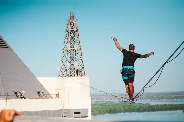 Un homme marche le long d'une ligne tendue entre deux bâtiments. Un homme atteint l'équilibre en altitude. Highline sur la ville
. - Photo, image