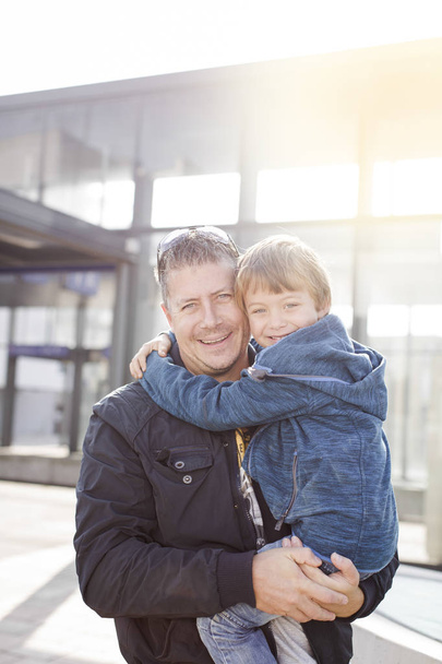 loving father with happy son in casual outfit posing in front of glass building - Foto, Imagem