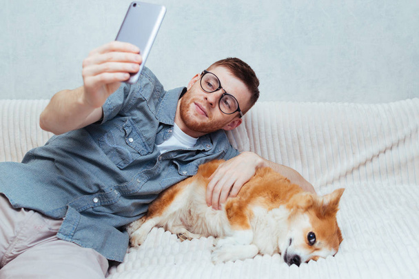Joven hace una selfie con un perro en el teléfono en casa
 - Foto, imagen