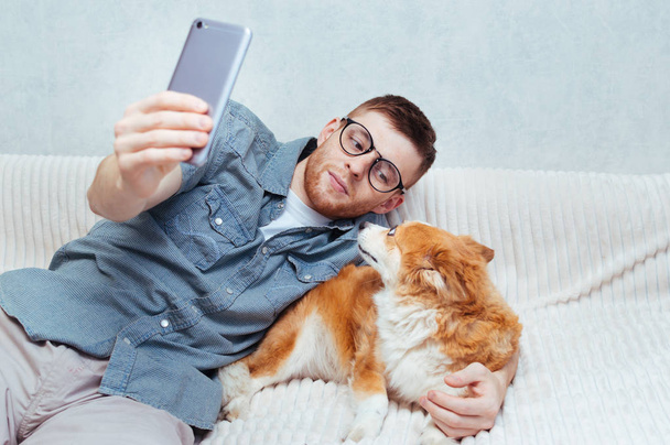 Young guy makes a selfie with a dog on his mobile. Concept blog - Foto, imagen