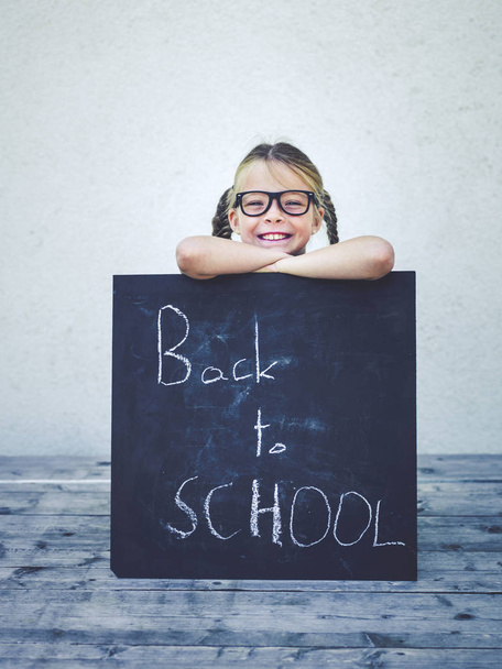 schattig klein meisje met bril bedrijf schoolbord met woorden terug naar school  - Foto, afbeelding