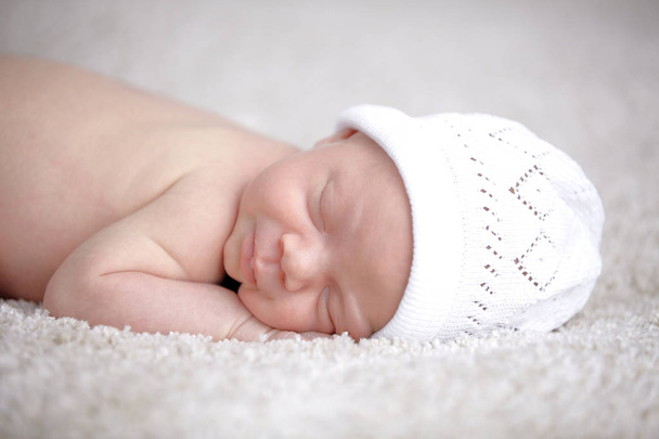 3 weeks newborn baby in white hat sleeping on coverlet  - Fotó, kép