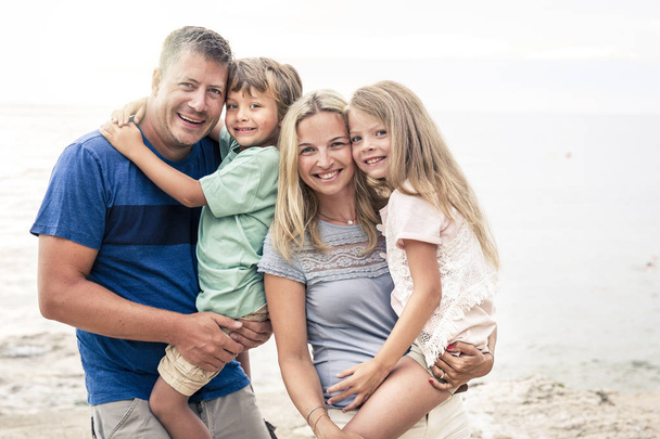 Счастливая семья с двумя детьми развлекается на пляже
 - Фото, изображение