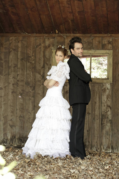 young beautiful bride and groom posing together in old wooden rustic building - Photo, image
