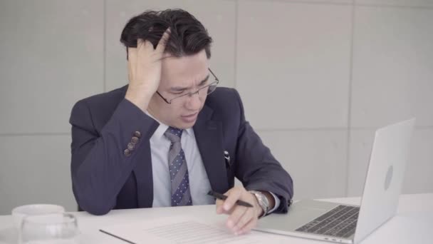 Slow motion - podnikatel naštvaná na stole v kanceláři. Asijský podnikatel otráveností prací v kanceláři. Yong obchodní člověka přemýšlet a nepracuje s stres předstírat, že položil ruku na hlavu. - Záběry, video