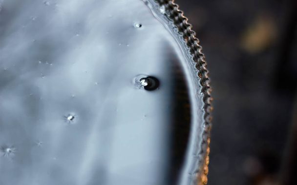 Bublbe on water surface in metallic barrel which looks like a full moon at night sky, crop, copy space, close-up - Foto, imagen