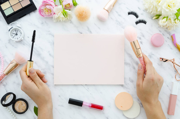girl is holding mascara in hands, copy space for handwritten quote pink notebook, lipstick, highlighter,make-up cosmetics on white background. Flat lay, top view. stylish female blogger concept. - Zdjęcie, obraz