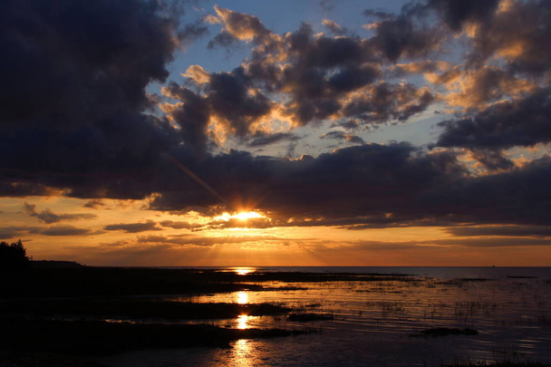 カラフルな夕日と海の上の暗い雲 - 写真・画像