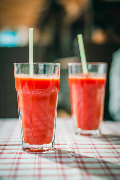 glass with tomato juice and a straw on the table - Foto, afbeelding