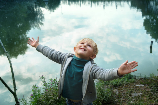 空を見て、水の近くの幸せな笑顔の少年 - 写真・画像