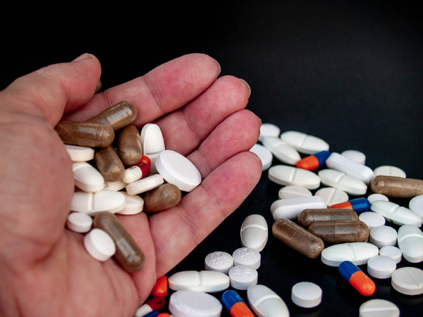 Une personne tenant des pilules de différentes tailles, formes et couleurs avec sa main. Concept de santé
 - Photo, image