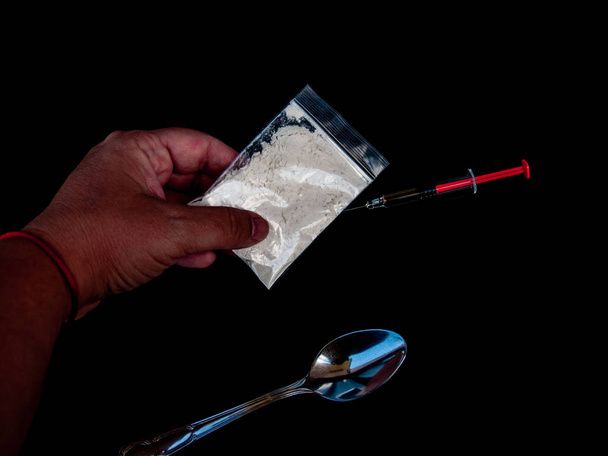 Die Hand einer Person, die Droge, ein Löffel und eine Spritze. Drogenkonzept - Foto, Bild