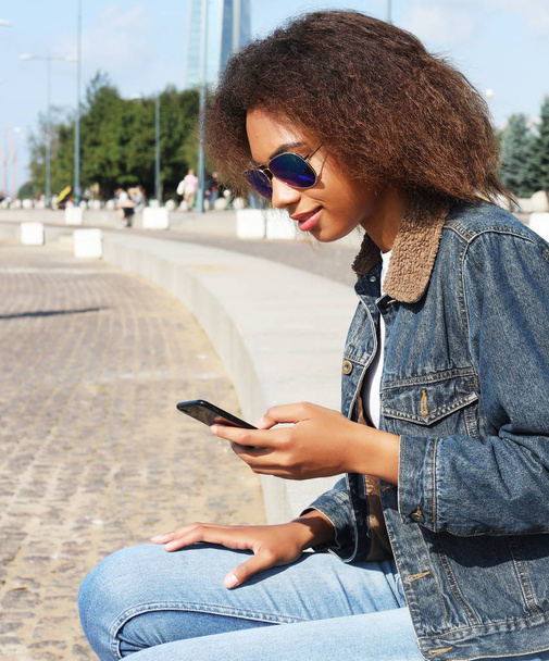 Beautiful afro american woman using mobile in the street. Communication and lifestyle concept. - Foto, Bild