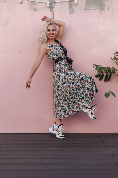 Счастливая красивая молодая девушка в модном платье прыгать возле розовой стены
 - Фото, изображение