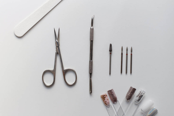 Scissors, nail file, manicure tool lies on a white table, Top view - Zdjęcie, obraz