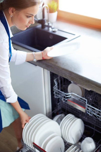 Dishwasher. Young woman in the Kitchen doing Housework. Wash-up - 写真・画像