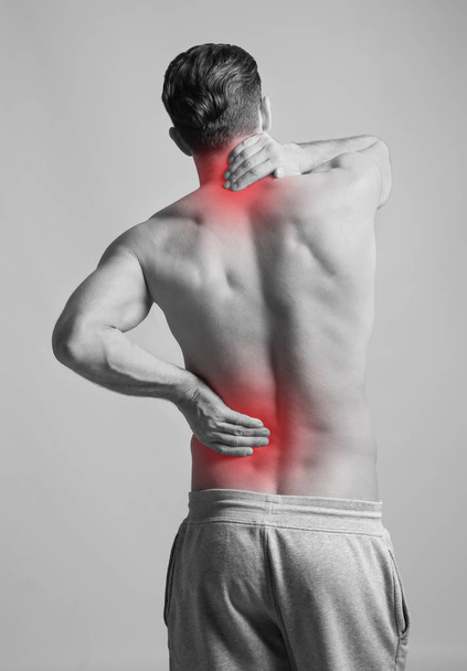 Man suffering from back pain on grey background, black and white effect - Foto, immagini