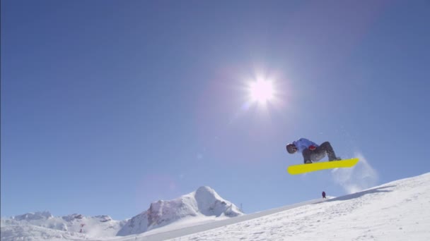 MOTION SLOW : Jeune snowboarder pro chevauchant le half pipe dans un grand snowpark de montagne, sautant du mur de half pipe et au-dessus du soleil, effectuant des tours et des rotations avec des saisies en hiver ensoleillé
 - Séquence, vidéo