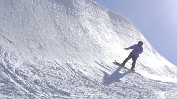 SLOW MOTION: Jovem snowboarder profissional montando o meio tubo no grande parque de neve da montanha, pulando alto da parede halfpipe, realizando truques e rotações com agarramentos no inverno ensolarado
 - Filmagem, Vídeo