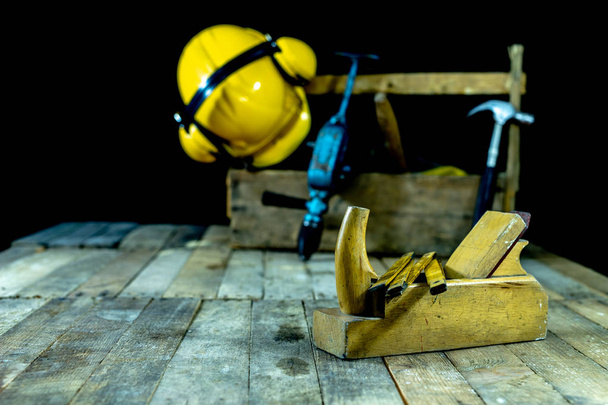 Box with accessories for the carpenter. Carpentry tools in a crate on a wooden workshop table. Dark background. - 写真・画像